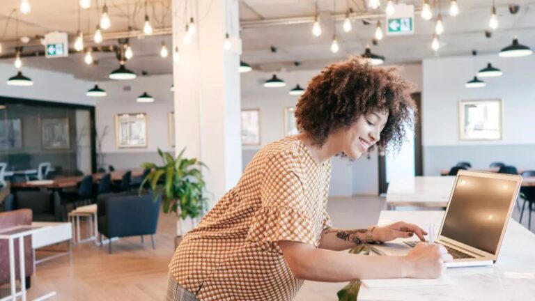 Smiling lady with a laptop over a desk